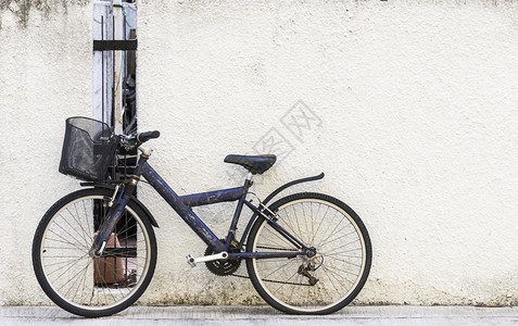 老旧运动自行车靠近老城水泥墙附的旧体育自行车座位城市的图片