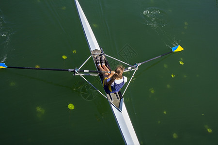 年轻女子在湖边的船上划水努力臭鼬图片