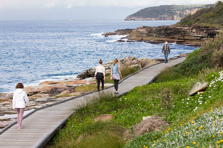 靠近在澳大利亚悉尼淡水湾附近的新南威尔士州海岸线上沿着木板路行走的人在澳洲悉尼淡水湾附近追踪海洋图片