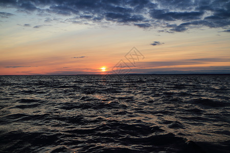 天空日落时傍晚的寒冷海滨戏剧化的景向日晒红色地平线升起艰难的海洋图片