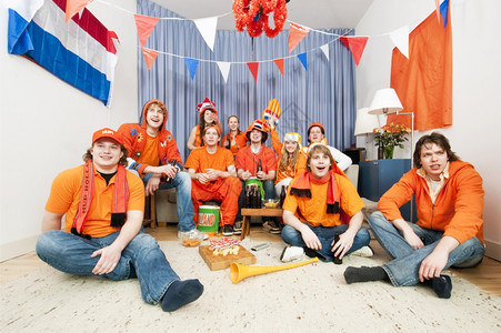 团体荷兰语足球迷坐在起居室看队的比赛观看本国队的比赛服饰图片
