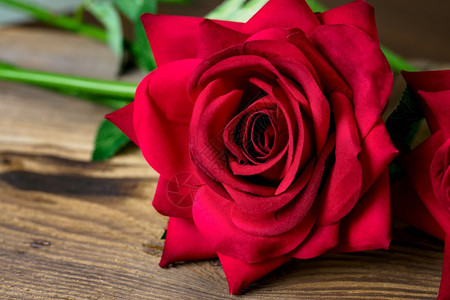 浪漫热情爱红玫瑰花从旧木板桌的织物上图片