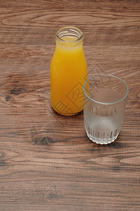 水果瓶装橙汁空杯子用木制背景隔绝传统的瓶子图片
