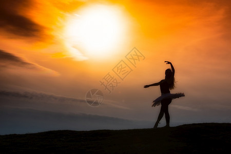 芭蕾舞漂亮的年轻Ballerina双月光在日落时山上独自跳舞图片