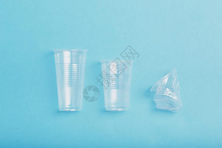 压扁的空塑料杯排成一在蓝色背景上收集塑料废物以回收污染和过多废物的概念复制文本空间目的碎一种图片