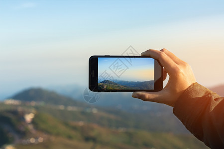 移动的相机电话使用手拍摄清晨照片山地景象的近身手图片
