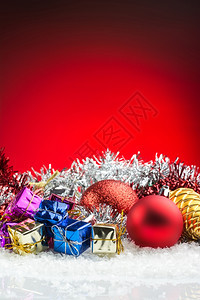 礼物庆典明亮的红底雪上圣诞饰品礼盒和球图片