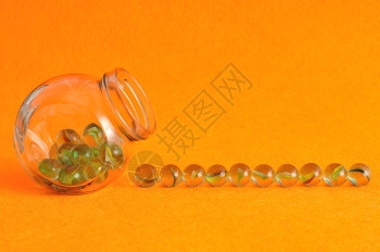 以橙色背景展示的玻璃罐中弹珠集装在玻璃罐中颜色透明非洲图片
