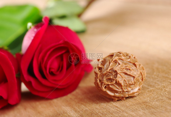 浅的木头红玫瑰在制板上牵着红玫瑰非常浅深的田地集中关注与红玫瑰一起的松露Truffle前方水平的图片