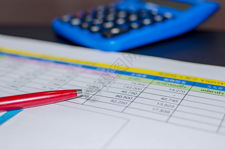 桌上的红笔和企业财务纸图销售量统计数据工作图片