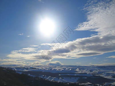 明亮的高太阳和乌云下加索山脉冬天景观图片