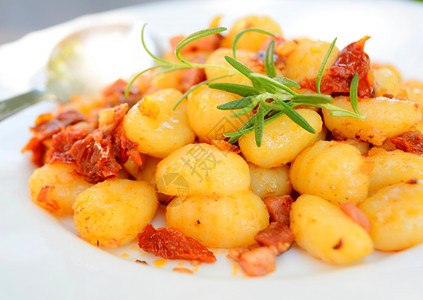 煮熟的食物白盘上加番茄培根和洋葱的格诺奇厨师图片