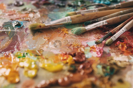 艺术家在木制调色板上涂刷和油画笔用油彩色调纸盘油漆刷子和调色板刀颜绿调图片