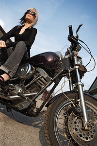 凉爽的一个坐在摩托车上美丽的金发女美城市的年轻图片