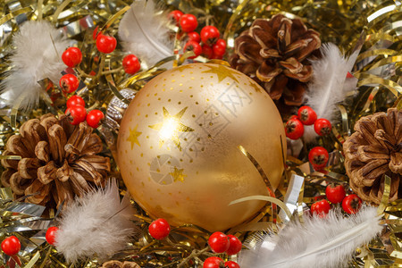 松树果羽毛红浆和金色的黄瓜放在作为圣诞节装饰品的金色罐头上假期快乐的图片