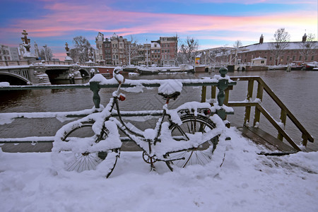 阿姆斯特尔暮屋日落时荷兰阿姆斯特丹市中心的雪地自行车图片