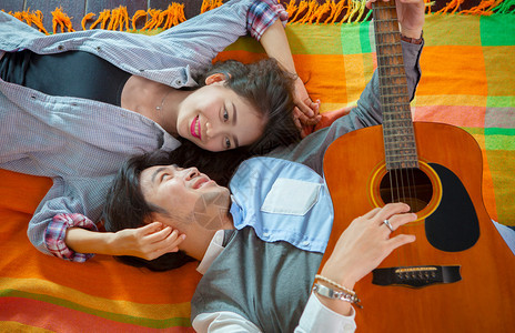 以轻松和快乐的情感弹吉他来的年轻女和亚裔男女情侣人音乐家假期图片