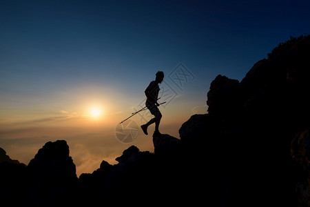 运动员美丽登山者在高脊上用电极攀爬的日落光影岭图片
