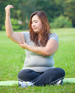 女肥胖年轻的亚洲女人检查她的手臂脂肪措施图片