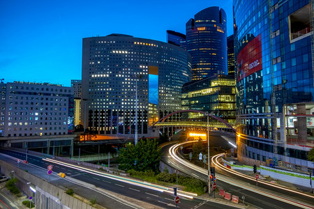 夜晚路巴黎晚间交通和现代大楼防卫区LaDefense巴黎晚间交通和现代建筑街道商业摩天大楼背景