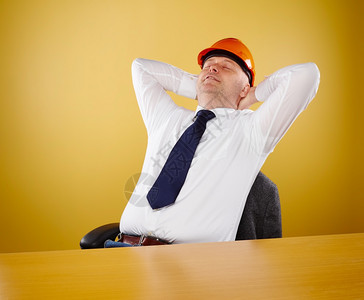 轻松白色的办公室男工程师他穿着白衬衫和领带头戴橙色硬帽子工作台图片