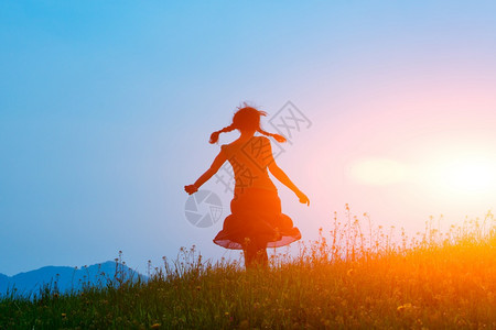 美丽的夏天日出落时在草地上自由行走的布丁女孩图片