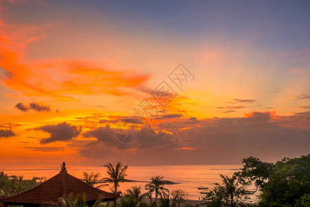 沙努尔丰富多彩的自然印度尼西亚岛巴厘海洋和滩上多彩的日落天空船棕榈树和传统屋顶巴厘海滩上的夕阳图片