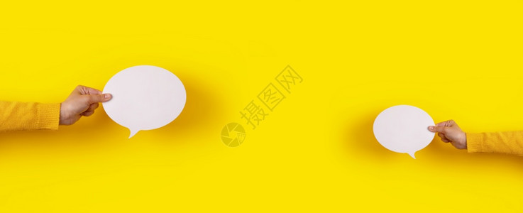 圆圈空的在黄色背景全布局上手握着两个空谈泡沫语言图标讨论图片