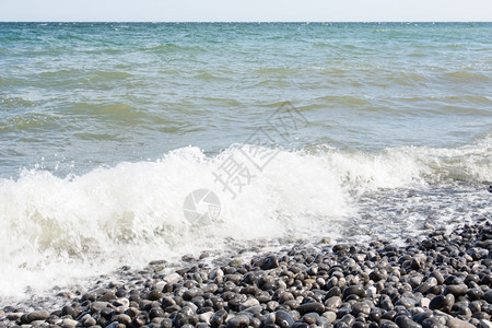 在海边有石块的面上挥舞波浪在海边有石块的戏剧岸水图片