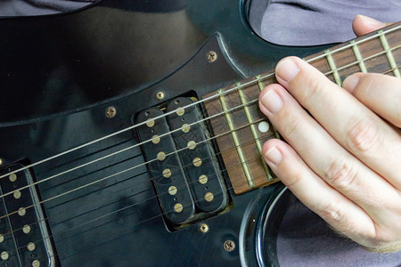 手指吉他年轻的在黑吉他上独奏主的人图片