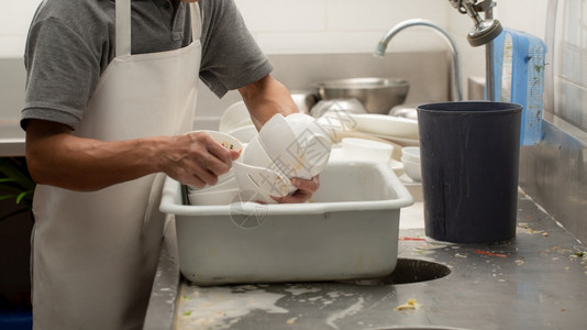 餐厅的洗碗员在水槽上家庭盘子肥皂图片