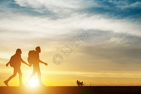 一对夫妇徒步帮助团队合作信任在一对夫妇徒步帮助团队合作过程中行走的轮休周游在日落期间行走男和女远足者在美丽的夜景中互相帮助每个登图片