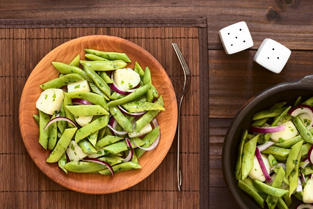 盘子绿色豆土和红洋葱沙拉配有鹦鹉类的面板木用自然光照黑木头香菜伴奏图片