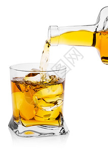 威士忌酒岩石从瓶装倒入透明玻璃用冰块隔开的立方体在白色背景上孤立威士忌从瓶装倒入有冰的透明玻璃金图片