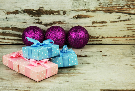 装饰风格四包彩色圣诞礼物放在旧木桌上底有三张紫色闪亮的胸毛浅深野外水平视图场地盒子图片