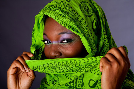 覆盖紫色的围巾一个无辜美丽年轻非裔女子的面容她用绿头巾和紫色化妆品蒙住嘴孤立无助地图片