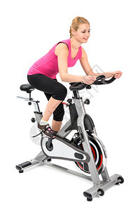 年轻的女子在旋转车轮运动上做室内骑自行车锻炼移动部分模糊不清身体的训练图片