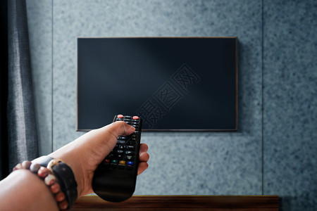 照片手指松弛观看电视概念手持机在现代生活室遥控制或改变频道放松的远程控制或改变中以远程为重点图片