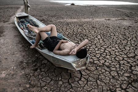 服装模型该男孩睡在渔船上双手放在干燥的地板上前额全球升温沙漠图片