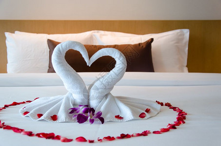 美丽内部的松弛室卧天鹅毛巾和床上的兰花酒店房间对夫妇来说是浪漫的图片