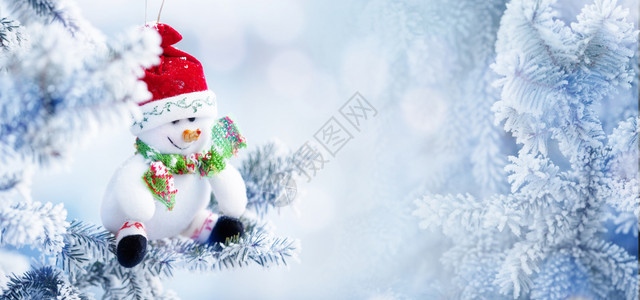 季节圣诞雪人在红色塔帽中的背景挂在雪冬森林的树枝上复制空间庆典冬天图片