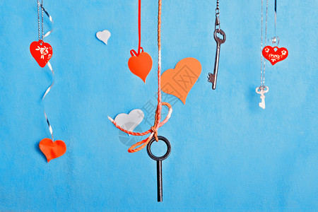 浪漫绳索婚礼钥匙和多彩红心挂在蓝背景的情人节或结婚贺卡上图片