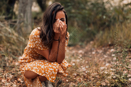 漂亮的年轻微笑女士穿着裙子在森林里蹲美丽着图片