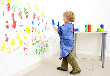 画家男孩走近墙壁她的手指绘画黄色艺术家淘气图片