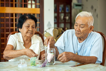 高龄夫妇用玻璃银行数钱节省高级的年长图片