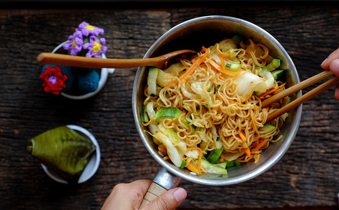 面条越南顶端观光紧闭人手将黄干即快面和蔬菜混合在一起黑木本底吃素食早餐人类图片