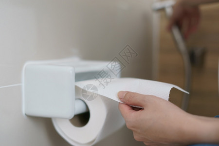 手拉着一卷卫生纸组织厕所干净的柔软图片