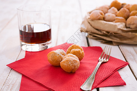 酒红色包素材背光甜的Castagnole典型的意大利嘉年华糖果红餐巾纸和一杯LiqueurCastagnole典型的意大利嘉年华甜传统背景