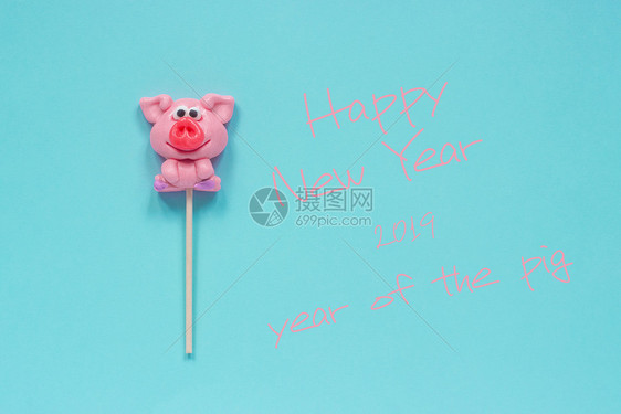 有趣的粉红猪棒糖和英文本新年快乐蓝色背景的猪年顶视图概念贺卡猪年棒糖和文本新年快乐的明信片最佳图片