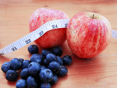 锻炼胖的测量苹果和蓝莓带有健康饮食的计量胶带概念图片